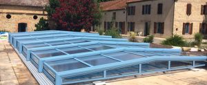abri bas de piscine en verre avec une structure alu bleue