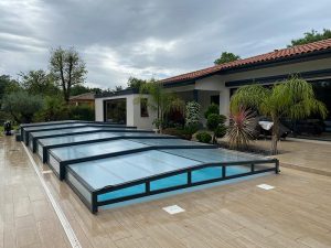 terrasse avec piscine recouverte d'un abri bas en verre cintré