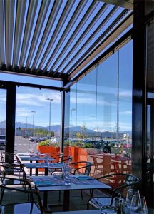 pergola bioclimatique à lames orientables pour restaurant avec parois de verre