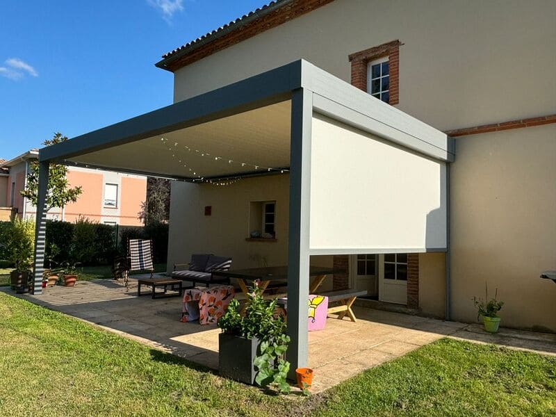 Pergola adossée à lames orientables avec store coulissant à moitié baissé