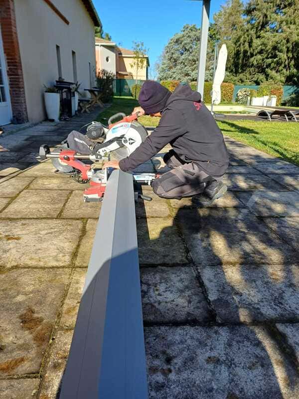 Découpe sur place des montants en aluminium de la pergola adossée